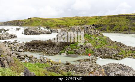 Un randonneur lumineux traverse la crique d'eau blanche en Islande Banque D'Images