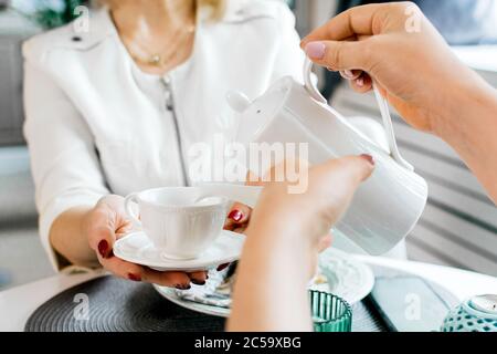Une femme verse du café dans une tasse pour le petit déjeuner Banque D'Images