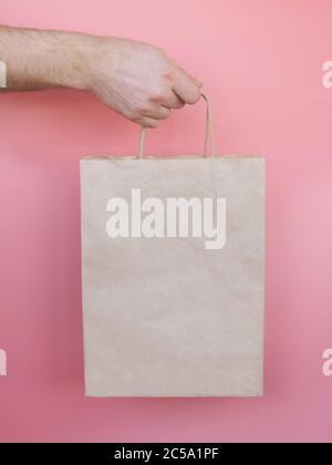 Homme tenant un sac de papier sur fond rose Banque D'Images