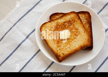 Toast maison au beurre sur une assiette blanche, vue en grand angle. Banque D'Images