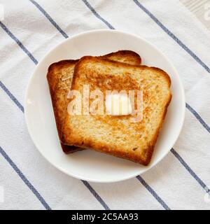 Toast au beurre maison sur une assiette blanche, gros plan. Banque D'Images