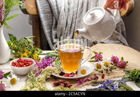 Une femme verse une tisane avec camomille, rosehip, trèfle. Cérémonie du thé. Boisson d'été Banque D'Images