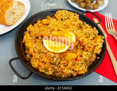 Savoureuse marinera de paella de Valence avec crevettes et pétoncles servi avec du citron sur du frypane de fer Banque D'Images