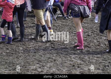 Des personnes dans des bottes en caoutchouc marchant dans la boue à la Festival de musique d'appel Standon Banque D'Images