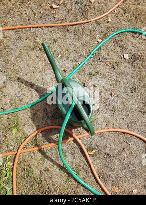 Arrosoir et tuyaux en plastique vert sur de l'herbe sèche en été Banque D'Images