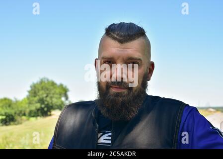 Homme avec une barbe sur fond de verdure. Grand portrait facial d'un homme barbu de 40 ans. Portrait plein visage. Banque D'Images