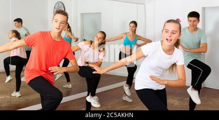 Adolescents gaies garçons et filles dansant chorégraphie de groupe synchrone dans la salle de danse Banque D'Images