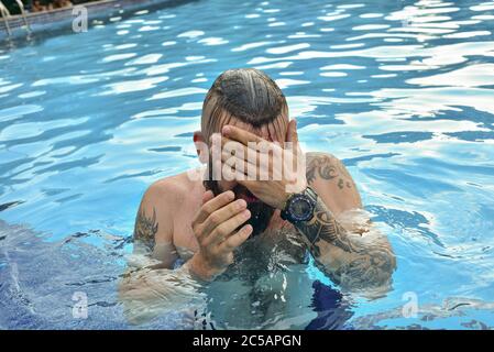 Homme barbu nageant dans une piscine. Homme avec une barbe dans la piscine. Banque D'Images