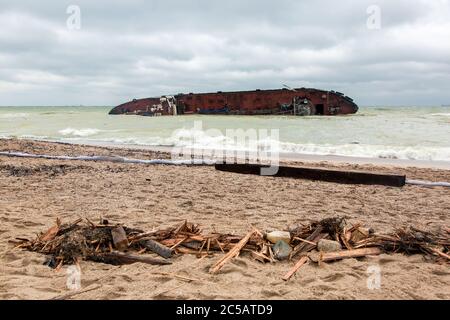 les conséquences d'une épave de camion-citerne sur une plage de sable une barrière protectrice et les restes de débris brisés de planches. Banque D'Images