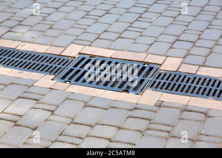 Réseau d'un système de revêtement de drainage sur un chemin constitué de carreaux de pierre carrée, en gros plan d'un système de drainage des eaux de pluie. Banque D'Images