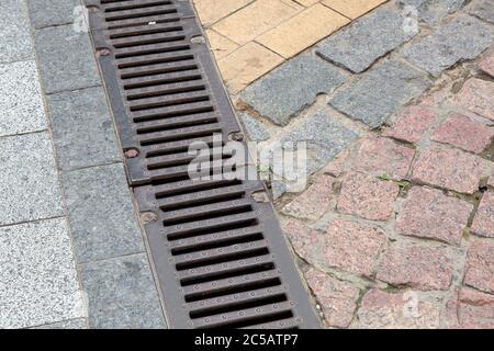 grille de drainage d'un système de tempête sur un trottoir piétonnier en carreaux de pierre, gros plan. Banque D'Images