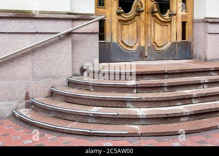 escalier en granit avec une montée à la porte d'entrée en bois, seuil avec marches à la porte d'entrée avec balustrade. Banque D'Images