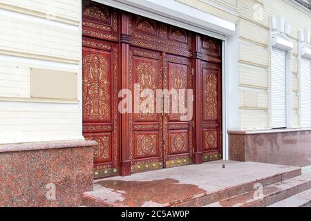 portes d'entrée en bois marron avec motif traditionnel sculpté à la main, seuil en granit et marches en pierre, vue latérale. Banque D'Images