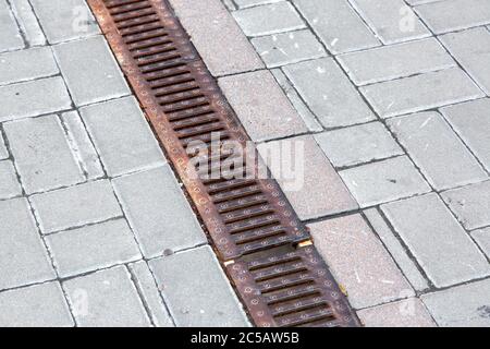 Réseau de rouille d'un système de revêtement de drainage sur un chemin de circulation en carreaux de pierre carrée, gros plan d'un système de drainage d'eau de pluie, personne. Banque D'Images