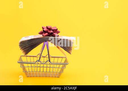 Sur les poignées du chariot d'épicerie se trouve un paquet de notes emballé avec un ruban cadeau et un noeud rouge Banque D'Images