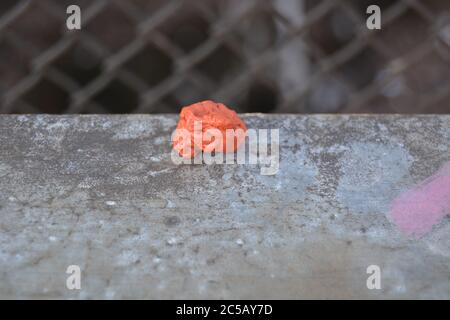 Chewing-gum orange au sol de la rue. Environnement.gomme à mâcher jetée en gros plan Banque D'Images