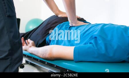 Physiothérapeute s'exerçant avec une personne handicapée sur une table de thérapie. Banque D'Images