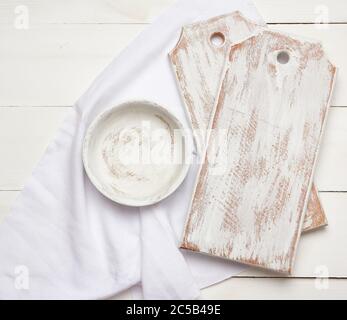 tableau blanc vide de découpe de cuisine et plaque ronde sur fond de bois, à côté d'une serviette en tissu blanc, vue du dessus Banque D'Images