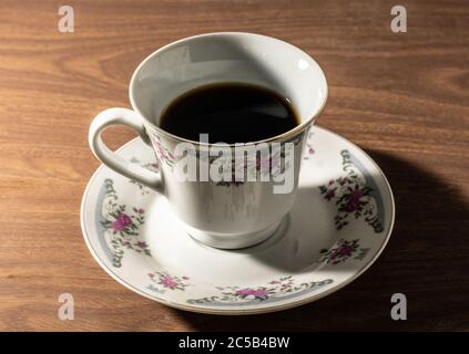 Gros plan d'une tasse de café de l'est remplie en deux et une soucoupe sur une table brune Banque D'Images