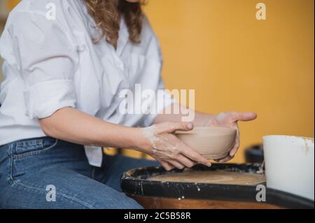 Femme potter travaillant avec de l'argile sur la roue en studio. Argile avec l'eau éclaboussé autour de la roue de potier. Banque D'Images