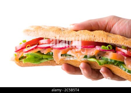 Main tenant des sandwichs sous-marins frais avec remplissage de fromage doux, saumon, laitue, concombre, radis, tomate et oignon de printemps. Tous au milieu Banque D'Images