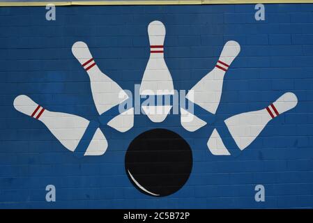 Un dessin de cinq quilles et une boule de bowling sur un mur de ciment peint en bleu dans une allée de bowling en Colombie-Britannique, Canada. Banque D'Images