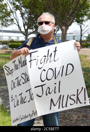 Fremont, CA - 15 juin 2020 : le protestataire devant la porte nord de l'usine de Tesla portant un masque facial. Demande de transparence sur les infections Covid 19 a Banque D'Images