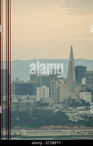 Vue floue de San Francisco depuis le Golden Gate Bridge avec des câbles de pont formant des bandes verticales au premier plan. Banque D'Images