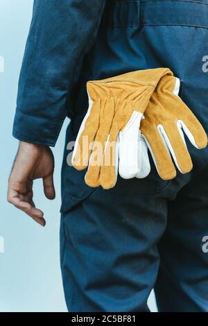 Gros plan sur les gants en cuir et mains du technicien mécanicien, en se tenant devant l'atelier d'entretien, préparation du technicien de maintenance pour le fixi Banque D'Images