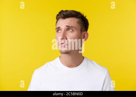 Concept de mode de vie, d'été et d'émotions des gens. Portrait de jeune homme fatigué et affligé, regardant dans le coin supérieur gauche avec une expression épuisée Banque D'Images