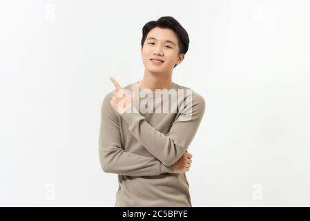 Souriant jeune asiatique beau homme pointant de la main vers un espace vide de côté Banque D'Images