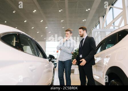 Un directeur des ventes homme confiant qui s'occupe de jeunes gens à la concession. Banque D'Images