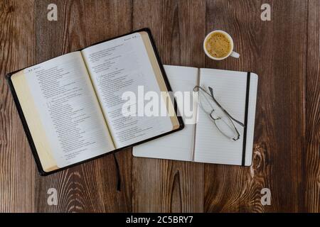 Los Angeles CA US 01 JUILLET 2020: Étude du matin avec la Bible sainte ouverte avec bloc-notes de tasse de café noir sur fond de bois Banque D'Images