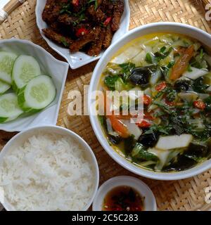 Plateau de repas vietnamiens avec vue sur le dessus pour le déjeuner sur fond blanc, plats végétariens faits maison avec frit de seitan, soupe de légumes, plat de riz, cuisine simple Banque D'Images