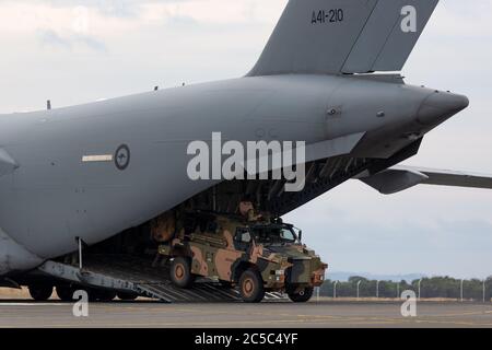 Le Bushmaster blindé du transport du personnel (APC) de l'Armée australienne déchargeant d'un Boeing C-17A Globemaster de la Royal Australian Air Force. Banque D'Images