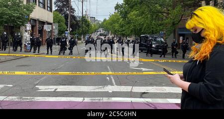 Seattle, Washington, États-Unis. 1er juillet 2020. La ligne de police face aux manifestants, le jour où ils ont repris leur quartier dans la zone CHAZ/CHAD, à Seattle, alors qu'on vérifie son téléphone cellulaire crédit: Amy Katz/ZUMA Wire/Alay Live News Banque D'Images