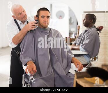 Jeune homme se coupe avec 37 professionnels de coiffure à salon de habile Banque D'Images