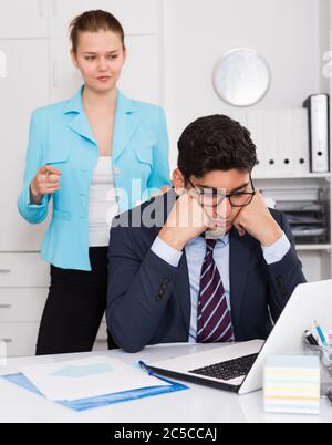 Frustrés businessman sitting at office desk sur l'arrière-plan avec femme en colère Banque D'Images