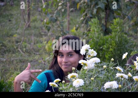 Une jeune fille indienne beauggul posant avec des doigts de pointage de plante florale blanche, sélectif Banque D'Images