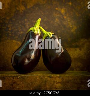 Aubergines fraîches et crues sur fond et surface marron Banque D'Images