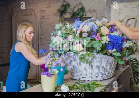 Deux artistes fleuristes professionnels, fleuristes en train de réaliser un grand panier floral avec des fleurs à l'atelier, fleuriste. Fleuriste, fait main, mariage Banque D'Images