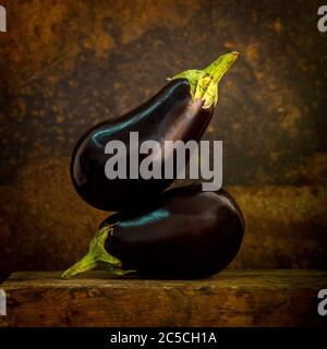 Aubergines fraîches et crues sur fond et surface marron Banque D'Images