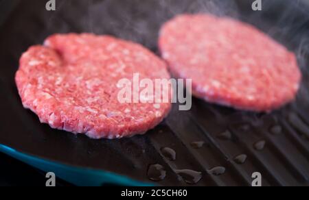 Concept de cuisson, de barbecue et de restauration rapide : gros plan de côtelettes de viande de hamburger rôtisant sur un gril plus brazier Banque D'Images