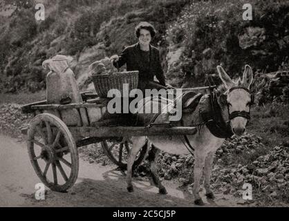 Vue du début des années 1920 d'une irlandaise dans le comté de Tipperary, qui se trouve à cheval sur la creamery locale, sur un chariot traditionnel tiré par l'âne, avec une urne de lait frais. Initialement photographié par Clifton Adams (1890-1934) pour 'Ireland: The Rock Wharce I was hewn', un reportage du magazine National Geographic de mars 1927. Banque D'Images