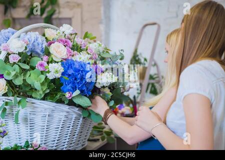 Deux artistes fleuristes professionnels, fleuristes en train de réaliser un grand panier floral avec des fleurs à l'atelier, fleuriste. Fleuriste, fait main, mariage Banque D'Images