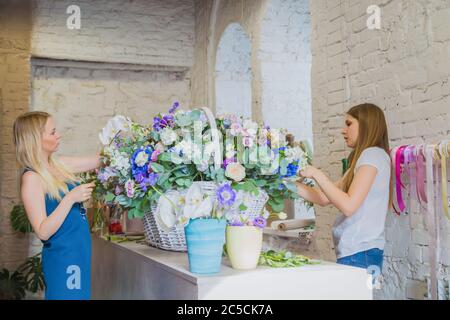 Deux artistes fleuristes professionnels, fleuristes en train de réaliser un grand panier floral avec des fleurs à l'atelier, fleuriste. Fleuriste, fait main, mariage Banque D'Images