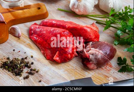 Cœur d'agneau frais et poumons sur planche à découper en bois avec assaisonnements. Cuisine maison Banque D'Images