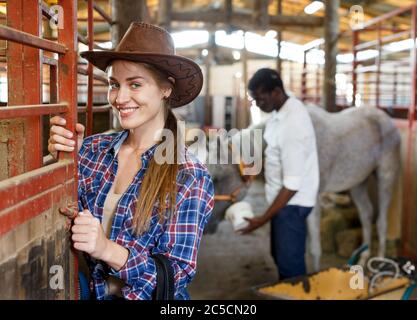 Portrait de jeune fille travailleuse agricole debout à horse stable Banque D'Images