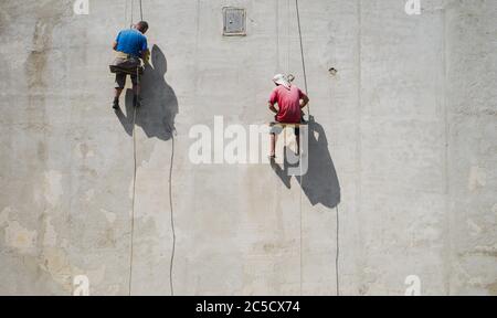 Le maître répare le mur. Pose du plâtre sur le mur. Les constructeurs masculins au travail. Contexte sur le thème de la construction. Banque D'Images