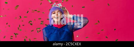 photo panoramique d'une jeune fille pop-art excitée dans une perruque pourpre et couronne sur la fête avec confetti, isolée sur rose Banque D'Images